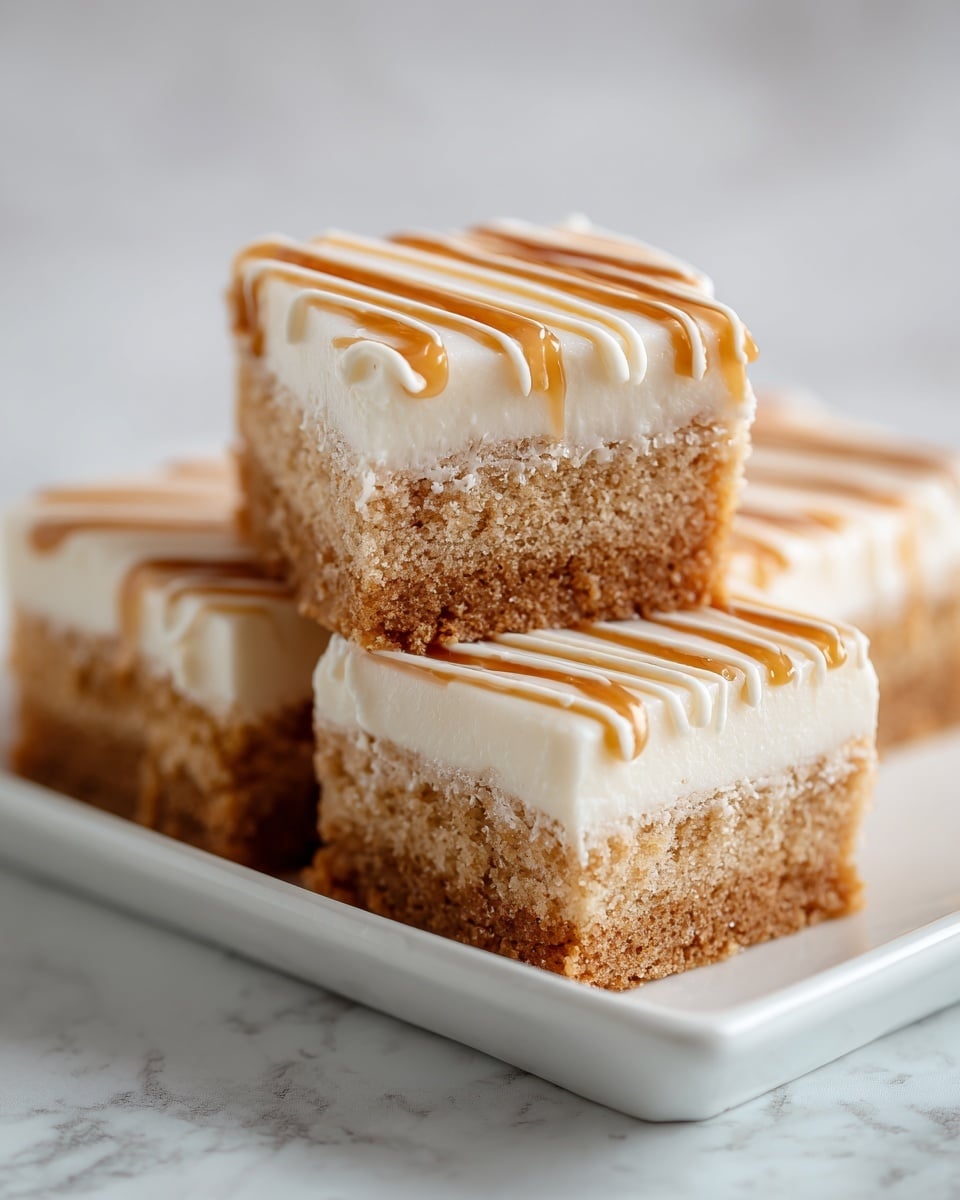 The image shows several square cake bars stacked on a white marbled surface, with one bar in the front held up by a woman's hand. Each bar has three visible layers: a light brown, soft and moist cake base; a thin, darker brown middle layer of cinnamon or spice; and a thick, smooth white frosting layer on top. The frosting is decorated with thin, wavy lines of light brown sauce or glaze, evenly spaced across the top. The texture of the cake looks soft and slightly crumbly, while the frosting appears creamy and rich. Photo taken with an iphone --ar 4:5 --v 7