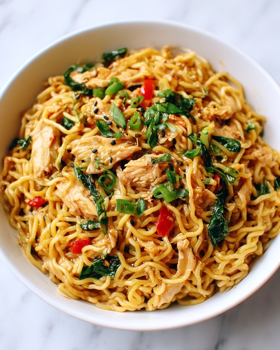 A close-up of a black bowl filled with stir-fried noodles, showing at least three layers: the bottom layer is cooked yellow noodles, the middle layer has small pieces of cooked chicken that are golden brown, and the top layer is scattered with chopped green onions and small red bell pepper bits, giving a fresh look. The noodles shine with sauce making them look glossy, and the green onions add a bright pop of color on top. The bowl is placed on a white marbled surface with a slightly blurred background. photo taken with an iphone --ar 4:5 --v 7