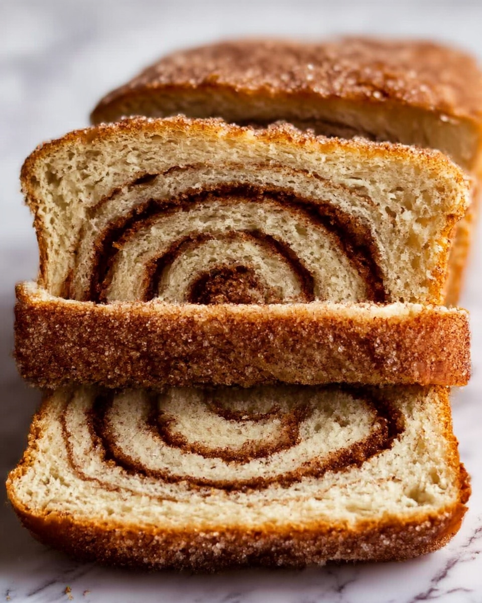 The image shows several slices of cinnamon swirl bread stacked closely together. Each slice reveals a soft, light brown inside with a dark brown cinnamon swirl running through the middle, spiraling from the bottom to the top. The top crust of the bread is golden brown, sprinkled with coarse sugar that adds a crunchy texture. The bread looks moist and fluffy with a slightly crisp crust. The slices are placed on a surface with a white marbled texture. photo taken with an iphone --ar 4:5 --v 7